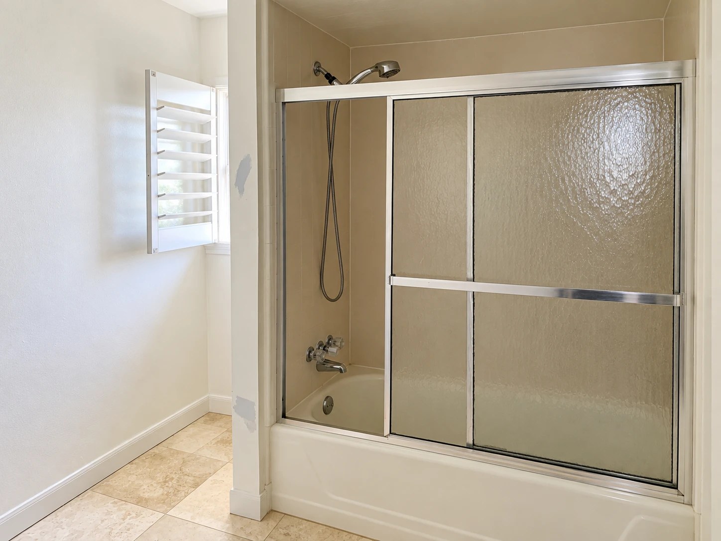 Bathroom before renovation: tub with sliding frosted-glass doors and beige surround