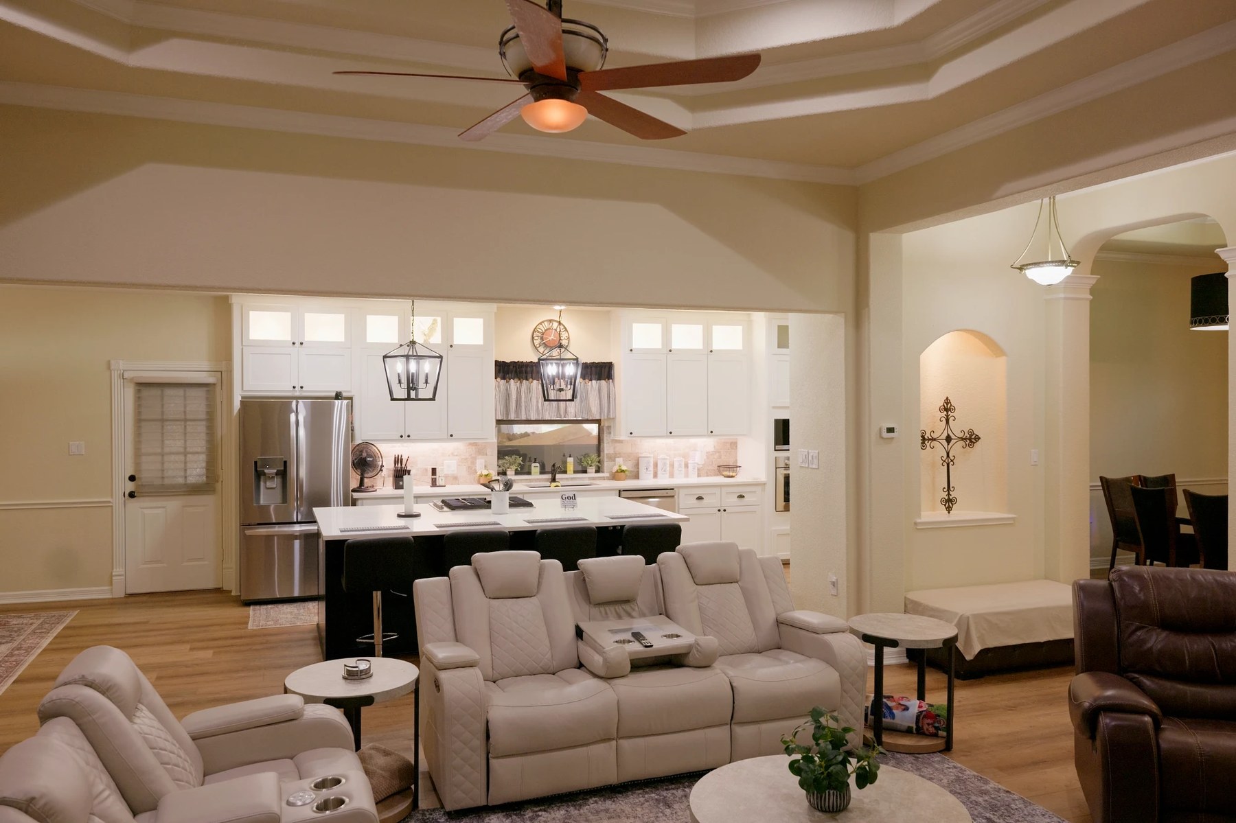 Open-concept living room and kitchen with white shaker cabinets, a large quartz island and lantern pendant lights
