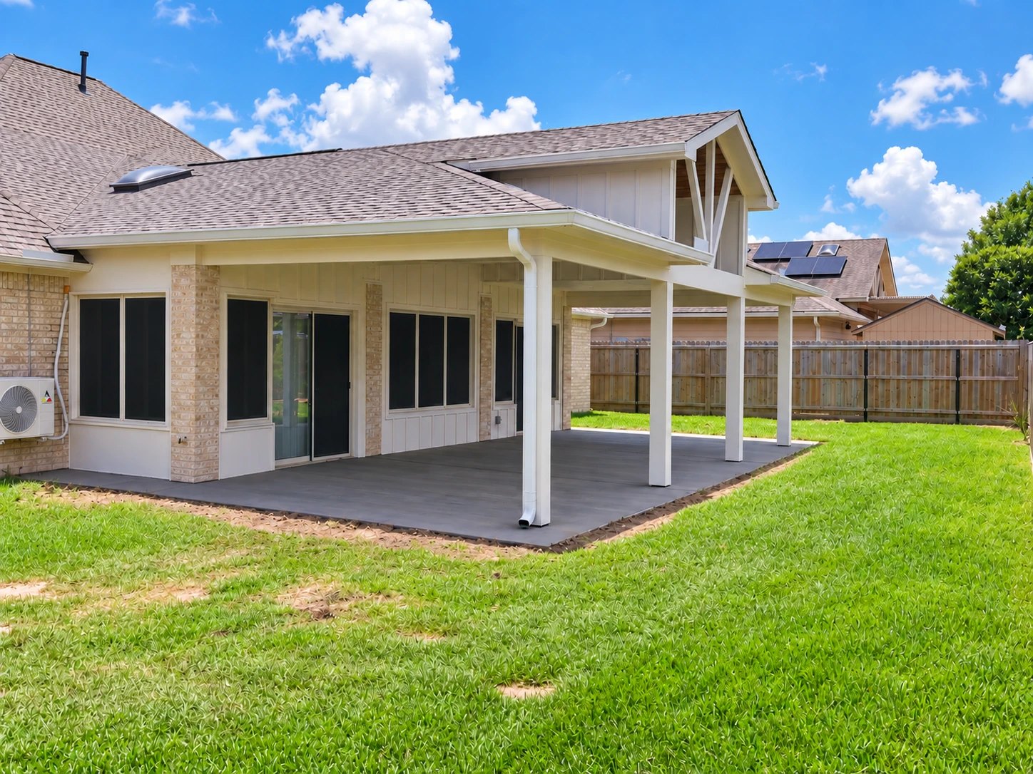 Back of the house after renovation: new covered patio with white posts, gabled roof and a poured concrete slab